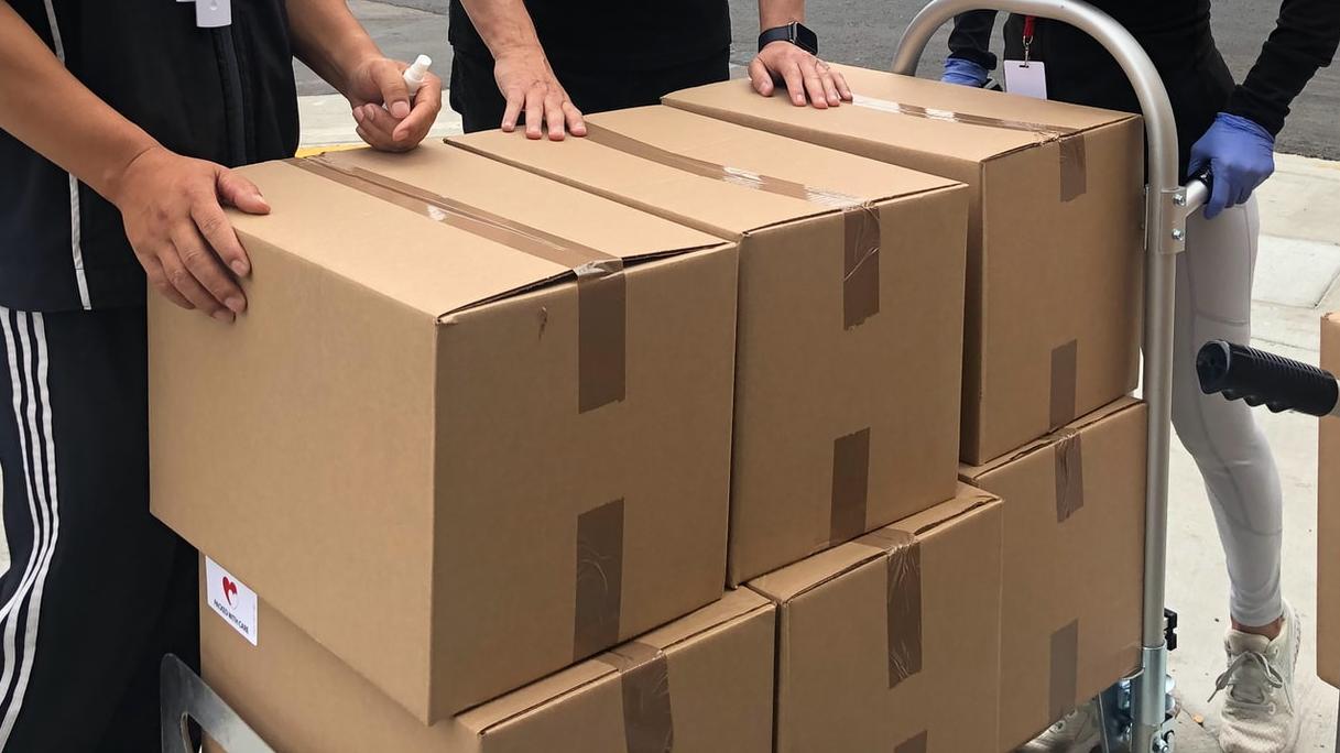 3 men in black polo shirt standing beside brown cardboard boxes